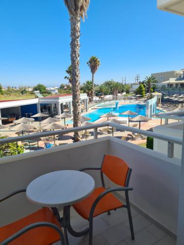 a balcony with a table and chairs and a swimming pool at Corali Hotel in Tigaki