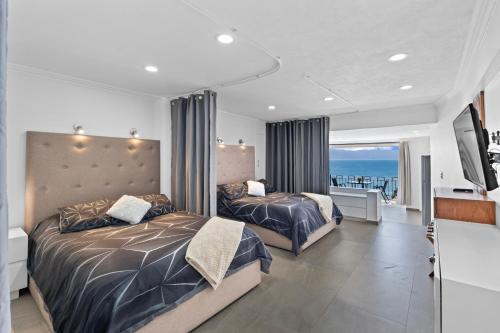 two beds in a bedroom with a view of the ocean at Luxury Condo just steps away from the Beach! in Puerto Vallarta