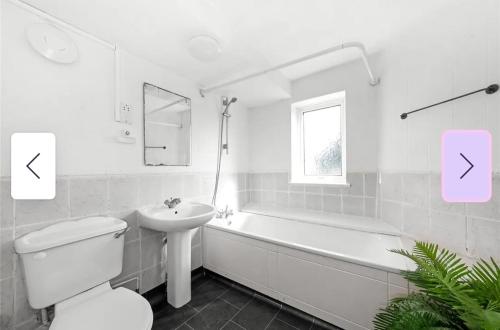 y baño blanco con lavabo, aseo y bañera. en Homestay CR7, en Thornton Heath