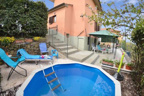 einem Pool mit Stühlen und einer Leiter neben einem Haus in der Unterkunft Casale Geniva with Private Pool - Happy Rentals in Massarosa