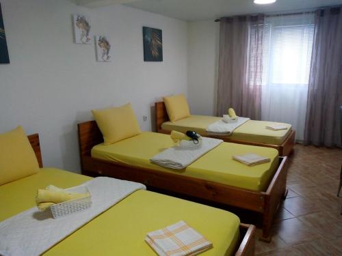a room with three beds with yellow sheets at Apartmant Lidija in Nov Dojran