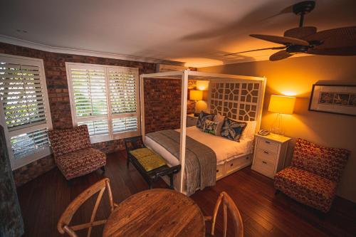 a bedroom with a bed and a table and chairs at Ballina Palms Boutique Motel in Ballina