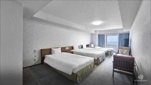 a hotel room with three beds and a window at Daiwa Roynet Hotel Naha Omoromachi in Naha