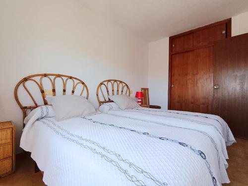a bedroom with a white bed with two wooden chairs at AyF ESPECTACULARES VISTAS DE MORRO DE GOS in Oropesa del Mar