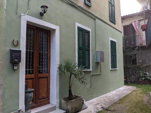 a green building with a wooden door and a potted plant at lake dreams in Verbania