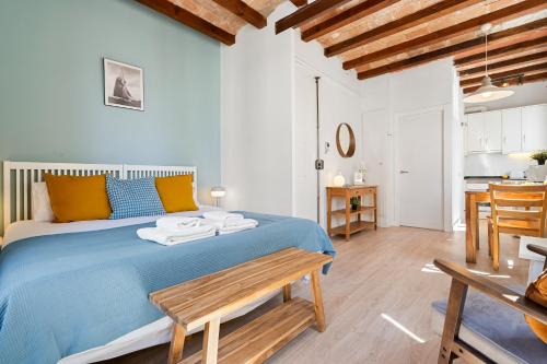 a bedroom with a blue bed with a wooden bench at Lodging Apartments Barceloneta Beach Studio 32 in Barcelona