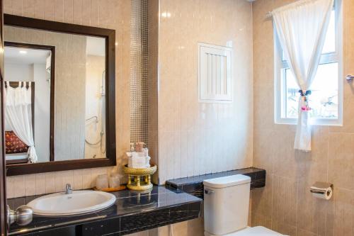 Un baño con lavabo, inodoro y espejo. en Aba Village حلال, en Chiang Mai