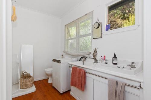 een witte badkamer met een wastafel en een toilet bij Kereru Cottage - Matapouri Holiday Home in Whangarei