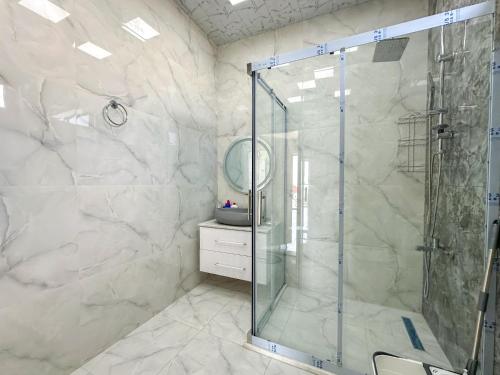 a bathroom with a shower with a glass shower stall at White Harmony House in Şamaxı