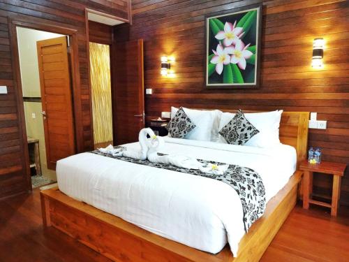 - une chambre avec un grand lit blanc et des murs en bois dans l'établissement Villa Cempaka Lembongan, à Nusa Lembongan