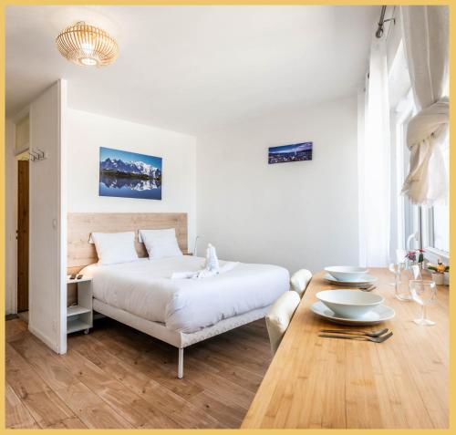une chambre blanche avec un lit et une table dans l'établissement Appartement Central I Annemasse, à Annemasse