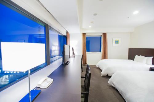 a hotel room with two beds and a large window at Hotel Sunroute Tokushima in Tokushima