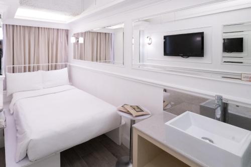 a white hotel room with a bed and a sink at Mini Hotel Causeway Bay in Hong Kong