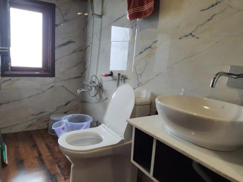 La salle de bains est pourvue de toilettes blanches et d'un lavabo. dans l'établissement Cozy Cove - Newly built 3BHK Duplex with rare valley view, à Shimla