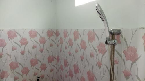 a shower head in a bathroom with pink flowers at Homestay Almadina Syariah in Jepara