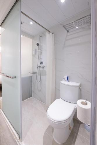 a white bathroom with a toilet and a shower at Mini Hotel Causeway Bay in Hong Kong