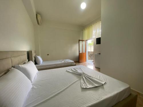 Un dormitorio con una cama blanca con una servilleta. en Guesthouse SELI, en Berat