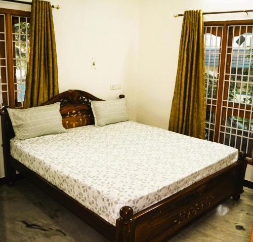 a bed sitting in a room with windows at Golden Gate Serviced Apartment in Chennai