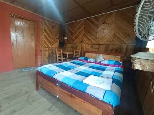 - une chambre avec un lit dans une pièce dotée de murs en bois dans l'établissement Ibankordor Jungle Resort, à Cherrapunji
