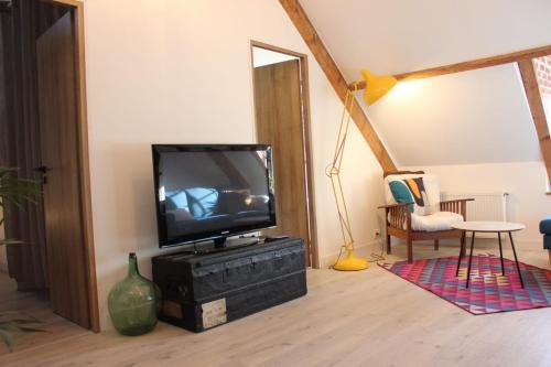 a living room with a television on a dresser at Les Jardins des 3 sœurs in Quettehou