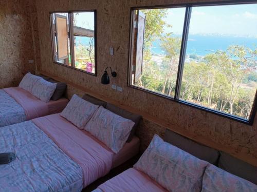 two beds in a room with two windows at Parinya Hill Homestay & Cafe Koh Larn in Ko Larn