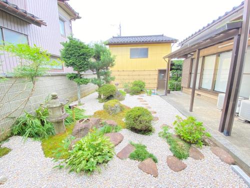 einen Garten mit Felsen und einem Hydranten vor einem Gebäude in der Unterkunft Guest house Yamabuki - Vacation STAY 13196 in Toyama