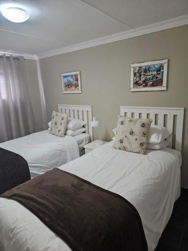 2 camas en una habitación con sábanas y almohadas blancas en Amberdale Estate Self Catering, en Queenstown
