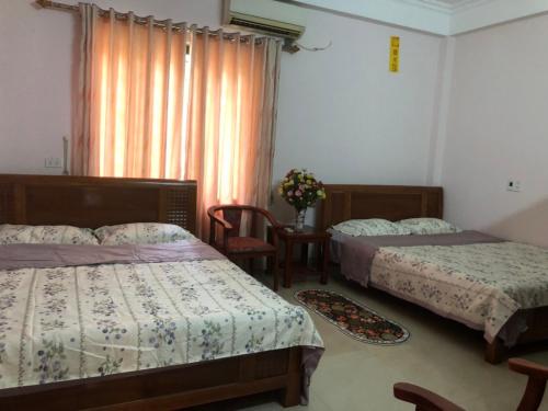 - une chambre avec 2 lits et une fenêtre dans l'établissement LyLy Homestay, à Dien Bien Phu