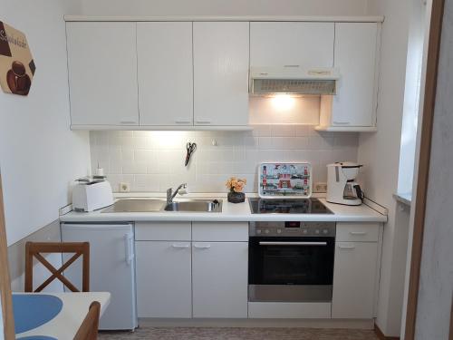 a kitchen with white cabinets and a sink at Ferienwohnung Kurparkblick in Bad Rodach