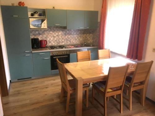 una cocina con mesa de madera y sillas y una cocina con armarios verdes. en Familienfreundliches Ferienhaus - b64026, en Marktgraitz
