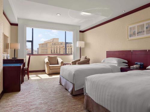 um quarto de hotel com duas camas e uma grande janela em Beijing Poly Plaza Hotel em Pequim