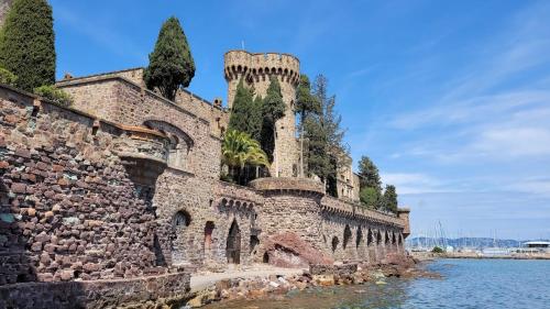 an old stone building next to a body of water at Hôtel de la Corniche d'Or in Mandelieu-La Napoule