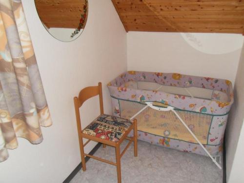 a small bedroom with a crib and a chair at Ferienhaus im schönen Frankenland in Marktgraitz