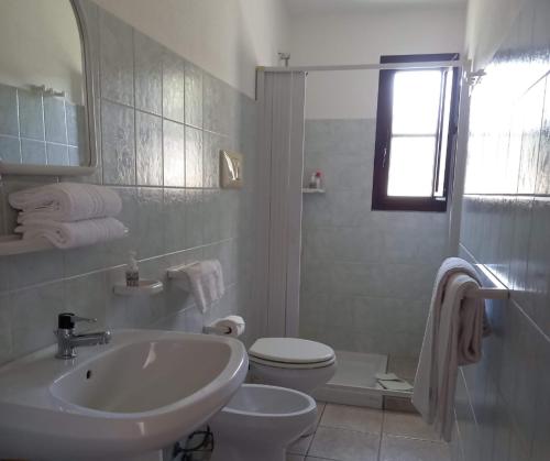 een witte badkamer met een wastafel en een toilet bij Agriturismo Su Cuile Countryside Comfort Rooms in Budoni