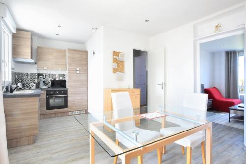 une cuisine et une salle à manger avec une table en verre et des chaises blanches dans l'établissement En bord de mer - Appt à moins d'un km de la plage, à Barneville-Carteret