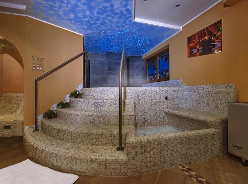 a bathroom with a bath tub and stairs with a blue ceiling at Hotel Garni La Vigna in San Michele allʼAdige