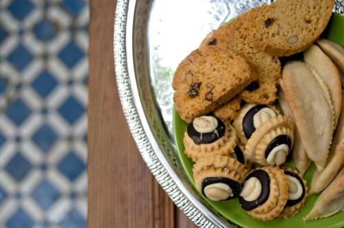 a green plate with cookies and snacks on it at Riad La Maison D'à Côté in Meknès