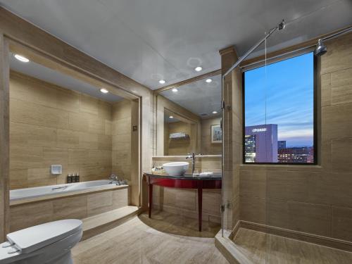 baño con bañera, lavabo y ventana en Beijing Poly Plaza Hotel, en Beijing