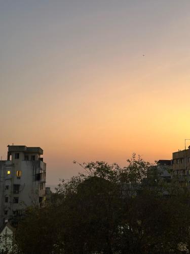 un coucher de soleil dans une ville avec des bâtiments et des arbres dans l'établissement Satguru building, à Mumbai