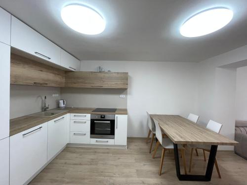 eine Küche mit weißen Schränken und einem Holztisch in der Unterkunft Apartmán Sadová Zlín in Zlín