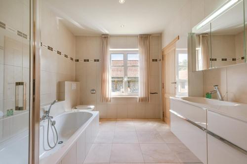uma casa de banho com 2 lavatórios, uma banheira e um WC. em Quiet and authentic vacation property with pond em Harelbeke
