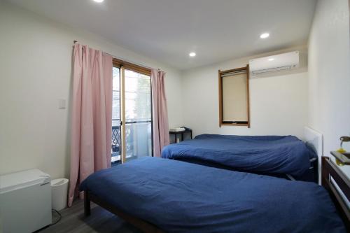 two beds in a room with a window at TOKYO MY HOME in Tokyo