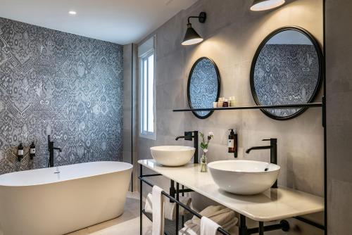 a bathroom with two sinks and a tub and mirrors at Vincci La Rabida in Seville