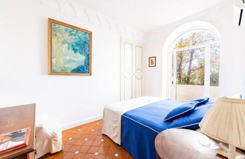 Un dormitorio con una cama azul y una ventana. en Villa Galeotta, en Marina Grande