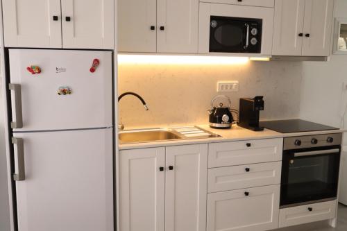 a white kitchen with a refrigerator and a sink at FOTEINI RESIDENCE in Kalymnos