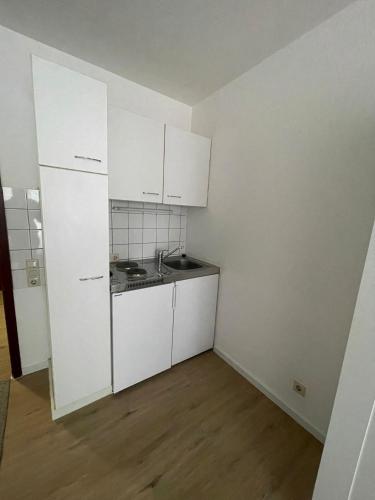 an empty kitchen with white cabinets and a sink at Wegener Aparthotel in Mannheim