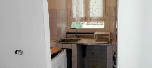 Elle comprend une petite cuisine avec un évier et une fenêtre. dans l'établissement Casa del PesceMatto, à Imperia