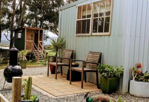 a patio with chairs and a table in front of a house at The Buddha Shed in Hindmarsh Valley
