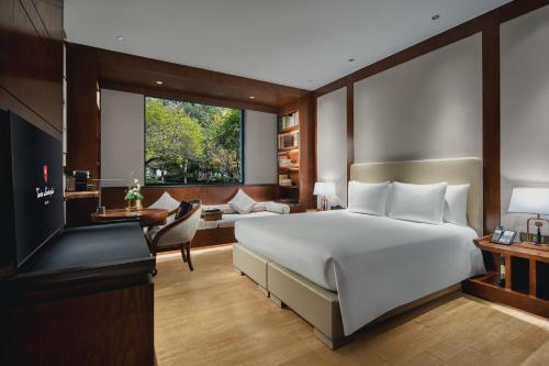 a bedroom with a large white bed and a desk at Tonino Lamborghini Hotel Suzhou in Suzhou