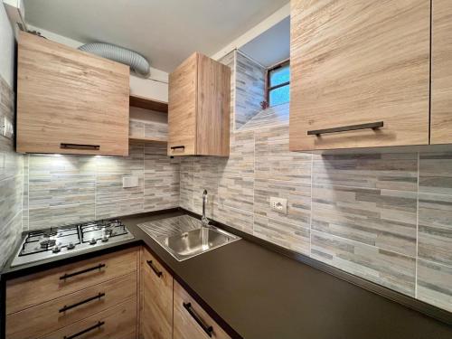 a kitchen with wooden cabinets and a sink at Appartamento con giardino privato. in Rubiana